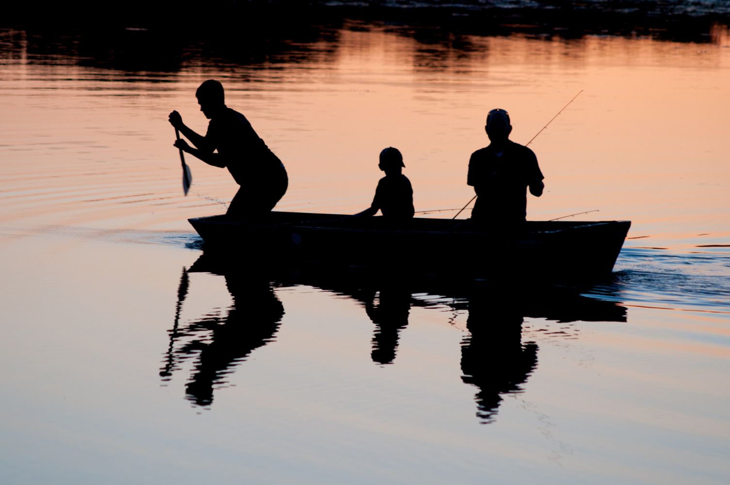 Family on a canoe at sunset in a lake.